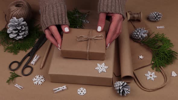 Woman packing Christmas gifts in brown paper alt