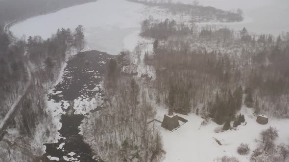 Aerial above Katahdin Ironworks during Winter snowfall TILTING ORBITING SHOT alt