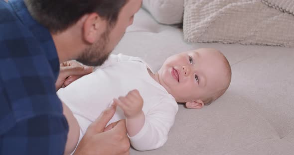 Close Up of the Baby Lying on Its Back on the Couch Smiling and Happy Looking at Its Father and alt