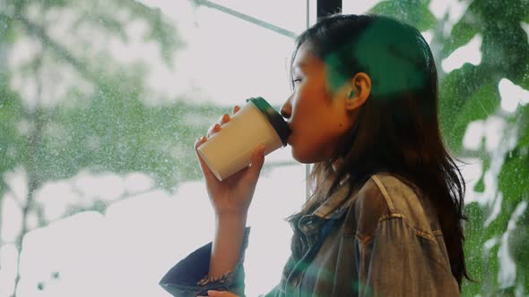 Businesswoman drinking coffee looking outside the window at the office.