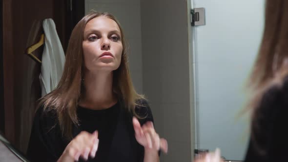 Girl Looks in the Mirror in the Bathroom alt