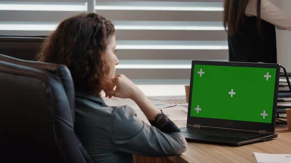 Side view business woman or female freelancer watching a webinar on green screen chroma key laptop. alt