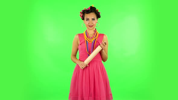 Girl with a Rolling Pin in Her Hands Seductively Looks at the Camera. Green Screen alt