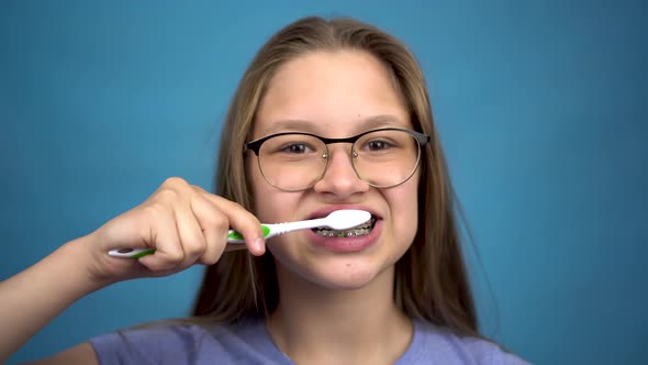Girl with Braces Brush Her Teeth with a Toothbrush Closeup. A Girl with Colored Braces on Her Teeth alt