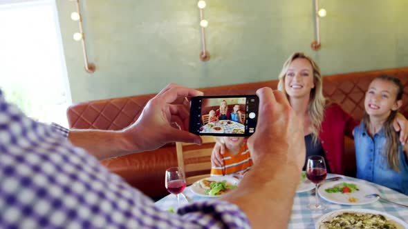 Man taking photo of his family with mobile phone 4k alt