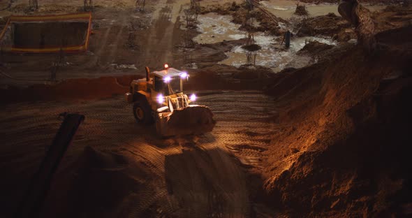 Front loader truck transports ground at construction building site at night alt