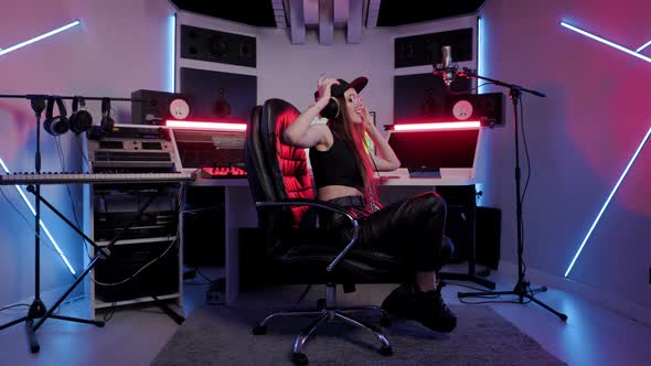 Soundwoman in Designer Glasses Cap and Headphones Enjoys Working in the Recording Studio