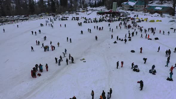 Aerial Slow Moving Shot of a Crowd Enjoying Themself in Snow Adventure Valley in Solang , Himachal alt