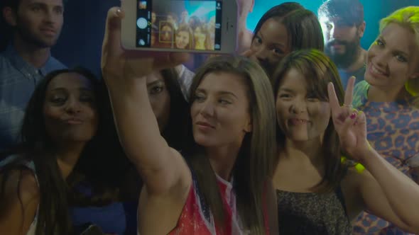 Woman taking self photograph with her friends at nightclub