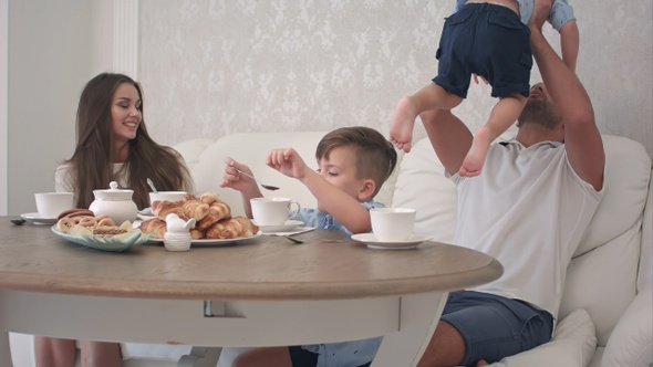 Happy family playing together while having breakfast at