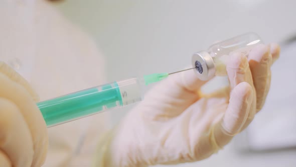 Medical worker in white gloves is preparing an injection. alt