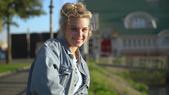 Slowmotion of Tender Beautiful Blond European Girl in Denim Jacket Leaning on Fence Turning at alt