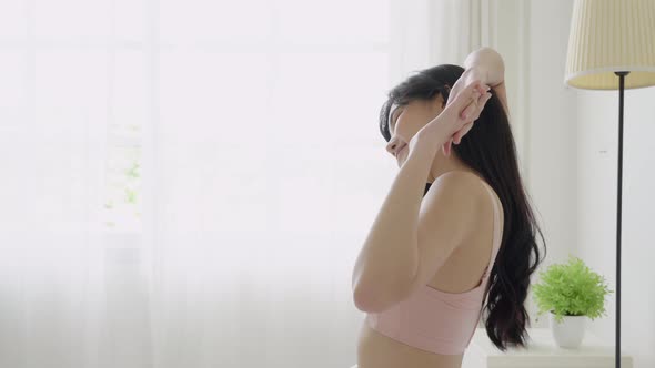 Beautiful young asian woman waking up in the morning and stretching on bed in the bedroom. alt