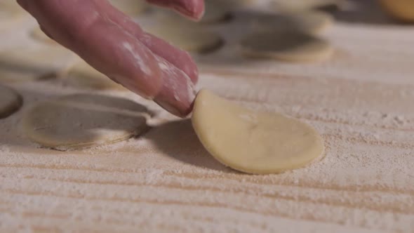 Female Fragile Fingers with Manicure Put on a Wooden Surface Dough Made for Dumplings