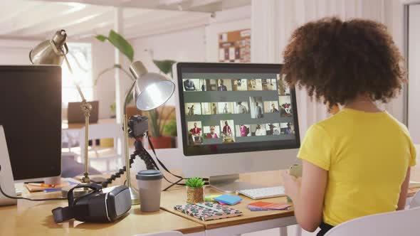 Mixed race woman working on computer in creative office alt