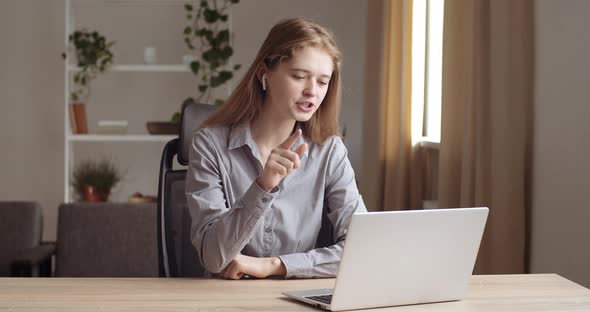 Portrait of Female Student Sitting at Home Wears Headphones Speaks with Teacher Online Through alt