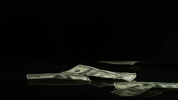 American $100 Bills Falling onto a Reflective Surface alt