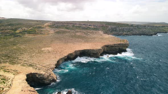 Aerial shot of sea waves crashing over the Popeye cliff of Malta. Set of Popeye Village, Malta alt