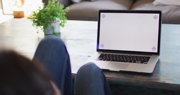 Biracial woman using laptop with copy space on screen at home alt