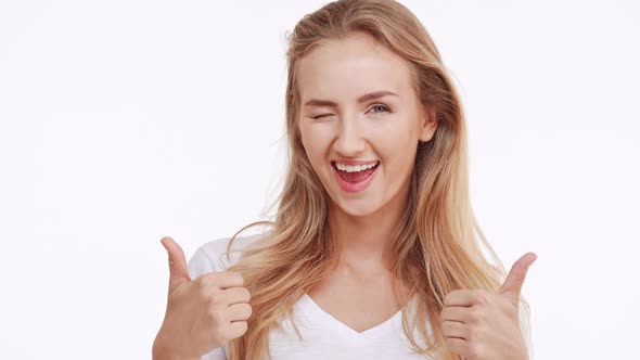 Young Beautiful Caucasian Blonde Girl Smiling at Camera and Showing Ok with Two Thumbs on White alt