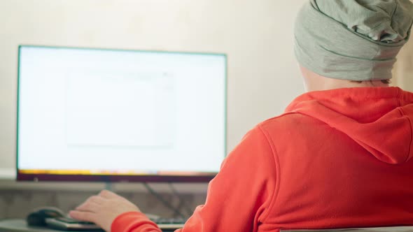 Man in a gray hat works at home while sitting at a laptop, remote work, copy space