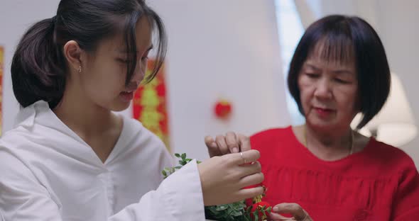 Asian Senior Woman And Niece Decorate House For Chinese New Year Celebrations. alt