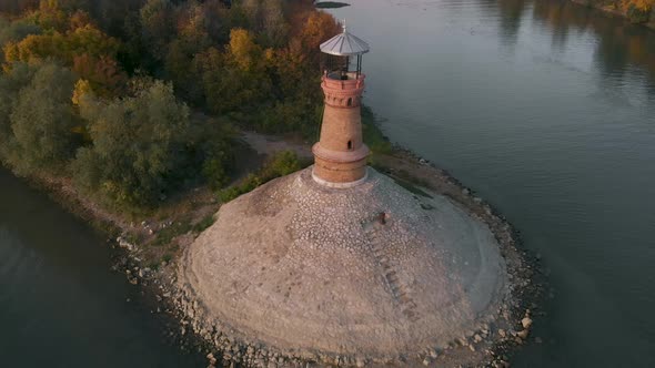 Amazing revealing drone footage of the old stone lighthouse by the Danube river. Beautiful autumn co alt