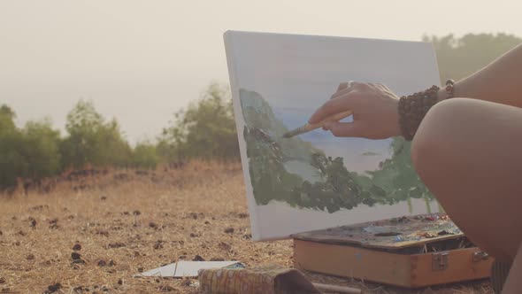 Close Up Side View of Woman Painting Artwork with Oil Brush Outdoors Country Background. Faceless alt