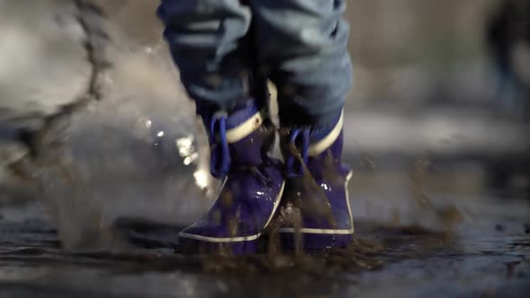 Happy Boy Rubber Boots Have Fun Playing in a Puddle on Road