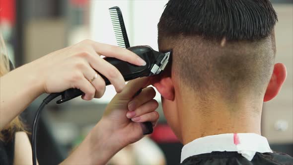 A Stylist Who Holds a Hair Clipper Removes Excess Hair From the Head of a Man alt