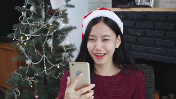 Young asian woman selfie video call online with friends in Christmas day on phone at home. alt