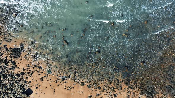 Stone beach and waves aerial shot alt