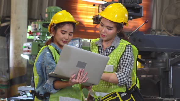 Two Asian female engineer workers working laptop discuss project at the factory