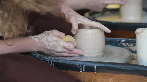 Young Woman Potter in Apron at Work. Craftsman Artist Shapes the Jug with Her Hands and a Special alt