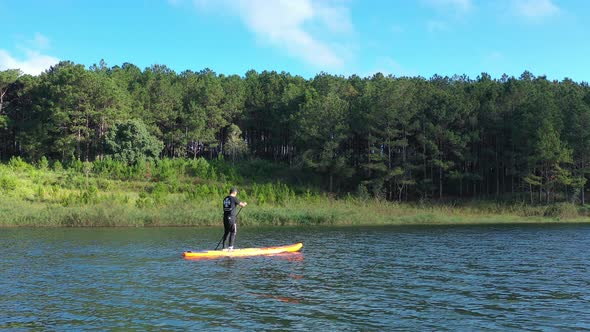 Aerial drone view of man is paddling on stand up paddleboarding in the mountain lakes