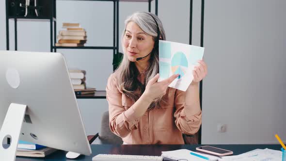 Mature Woman Demonstrates Documents and Reports By Videoconference Remote Work Online alt