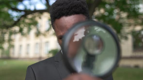 Closeup Portrait of African American Genius Scientist Posing with Magnifying Glass Outdoors alt