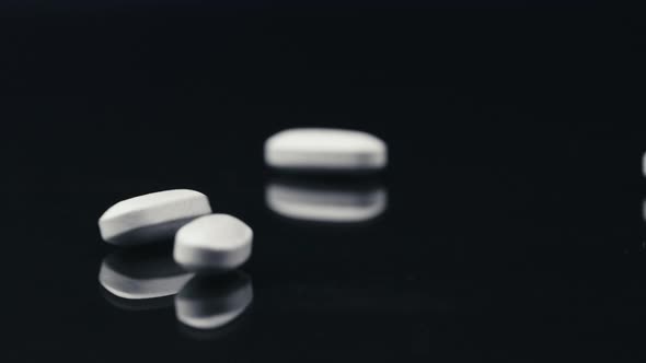 White Pills Falling on a Black Mirror Surface alt