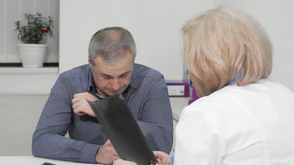 Mature Man Coughing at Medical Appointment with His Doctor alt