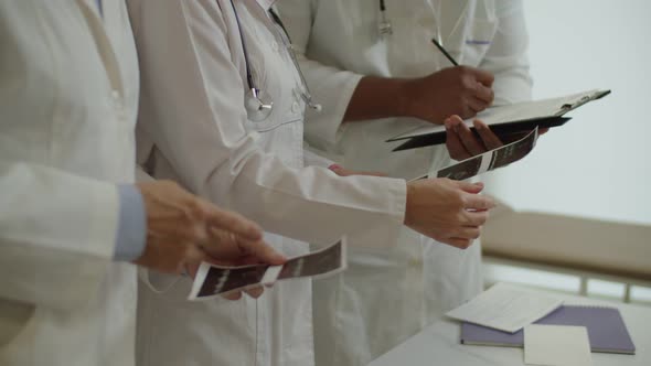 Hands of Diverse Multiracial Healthcare Workers Examining Ultrasound Scans at Medical Office alt