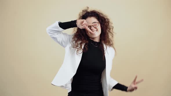The Distracted Young Woman with Curly Hair Dances with Her Fingers in the Shape of a Peace Sign alt