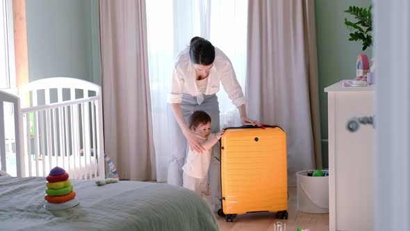 Mother and Baby Girl with Yellow Suitcase Baggage and Clothes Family Ready for Traveling on Vacation alt