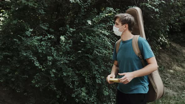 Caucasian Young Man with a Medical Mask on Face Is Walking in the Park alt