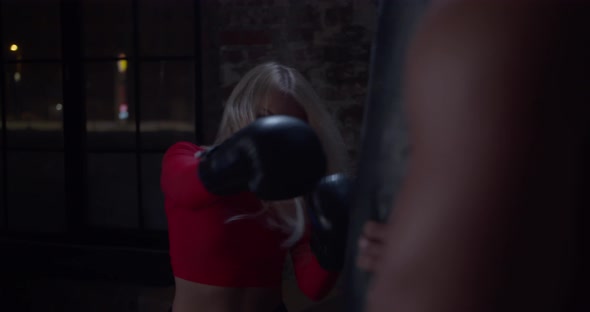 Boxing Coach Giving a Private Training To a Female Athlete Practicing a Punch in Urban Gym