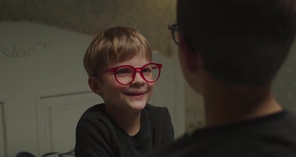 Preschool Cute Boy in Red Eyeglasses Talking To His Brother Sitting in Front of Him alt