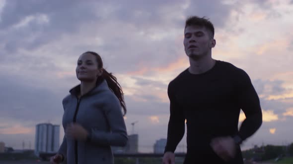 Athletic Couple Jogging on City Street in Evening alt