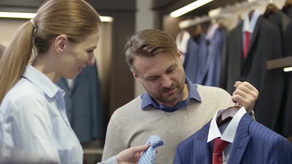 Sales Assistant Helping Man Choosing Necktie alt