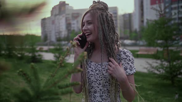 Young and Beautiful Girl Talking on a Smartphone in the Street