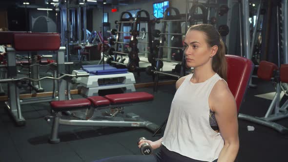 A Hard-working Girl Is Training Her Arms with Dumbbells