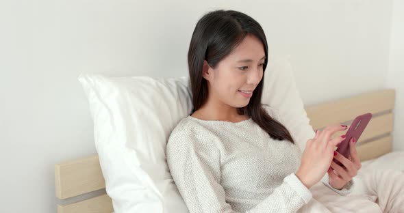 Young woman use of mobile phone on bed alt